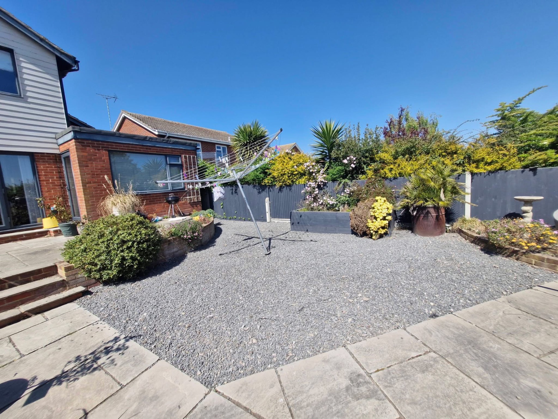 Gravel garden with sandstone patio steps and mature planted borders
