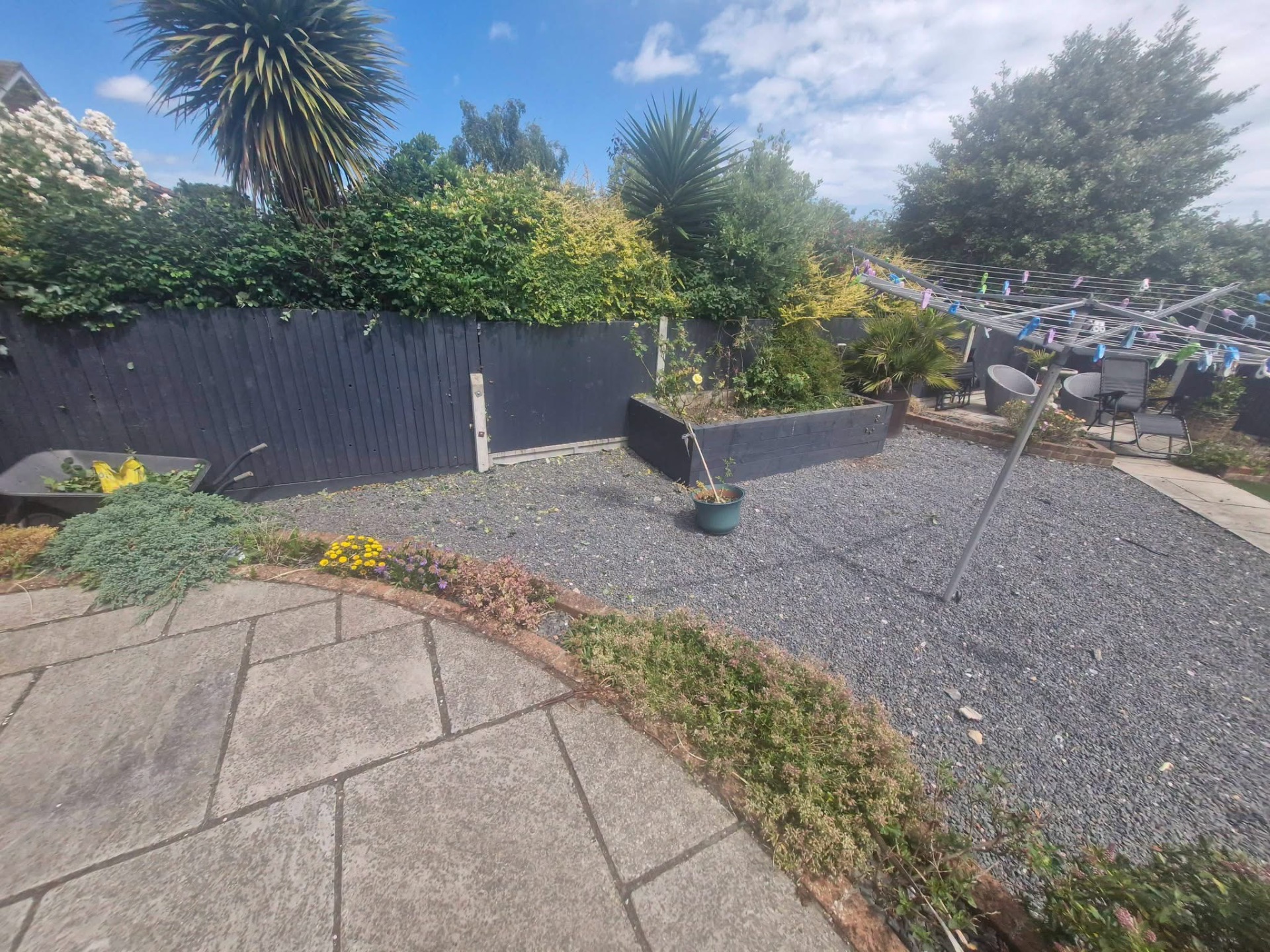 Gravel garden with raised sleeper bed and mature hedge boundary