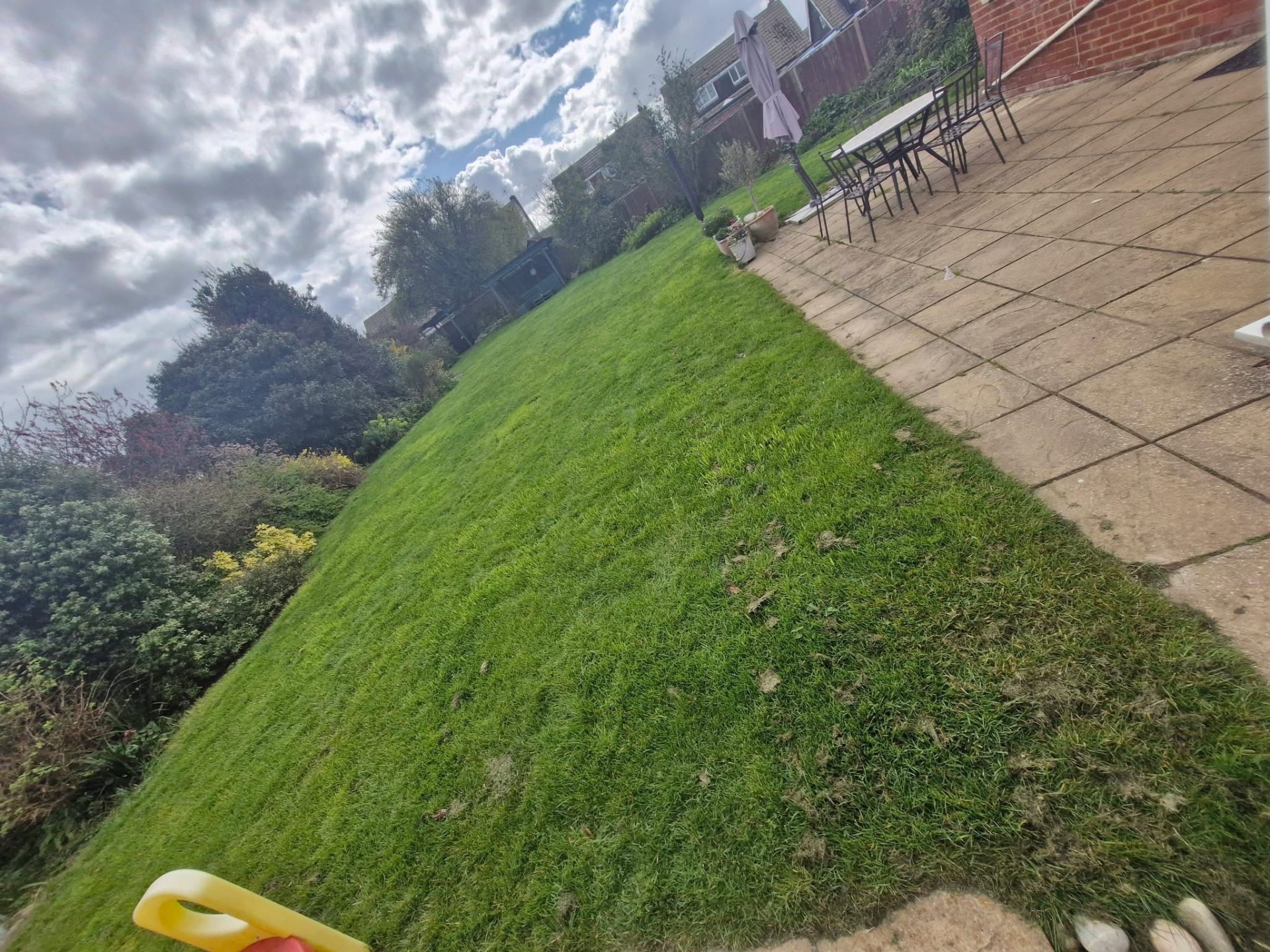Rear lawn freshly cut alongside patio with outdoor dining set