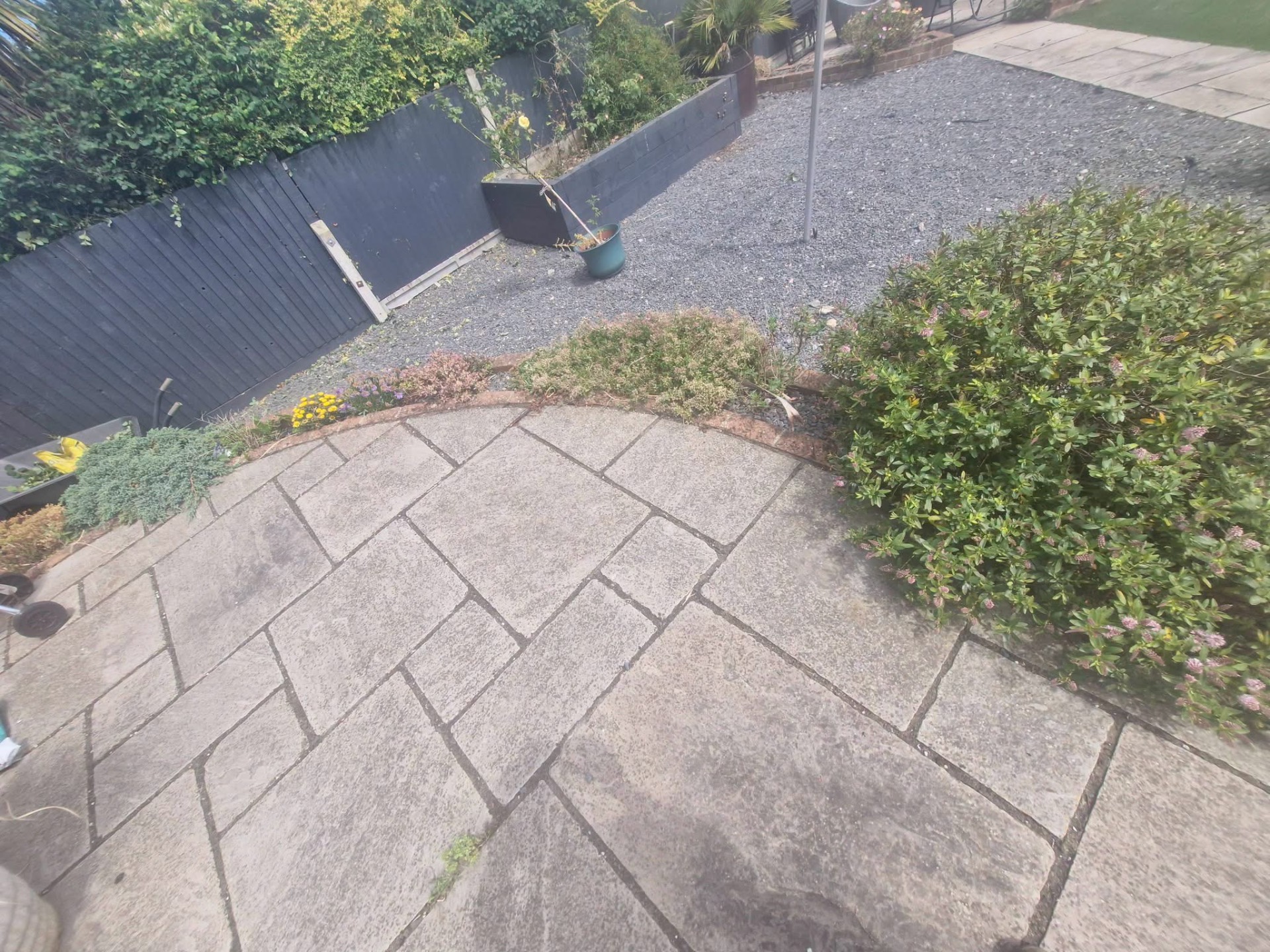 Circular sandstone patio with planted border and gravel garden beyond