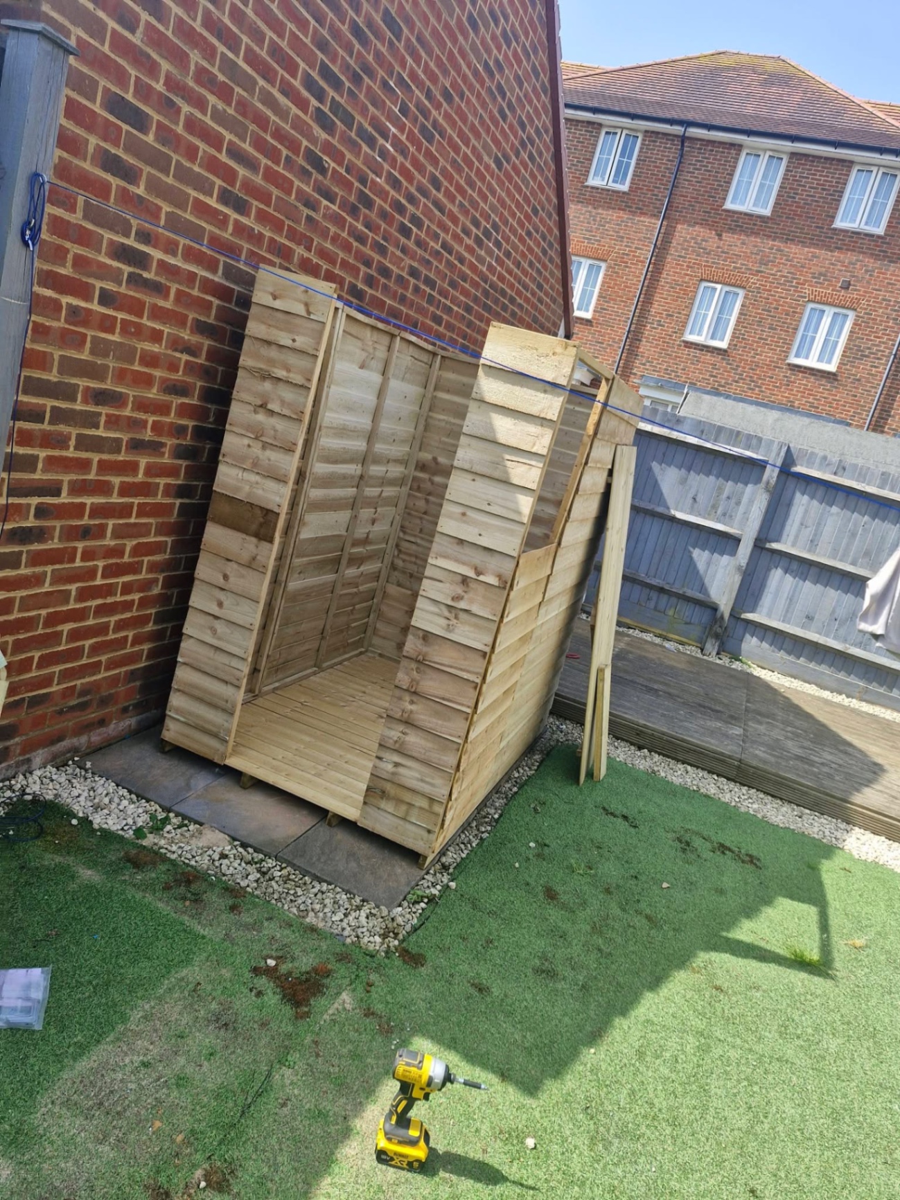 Timber log store built against brick wall on pebble base
