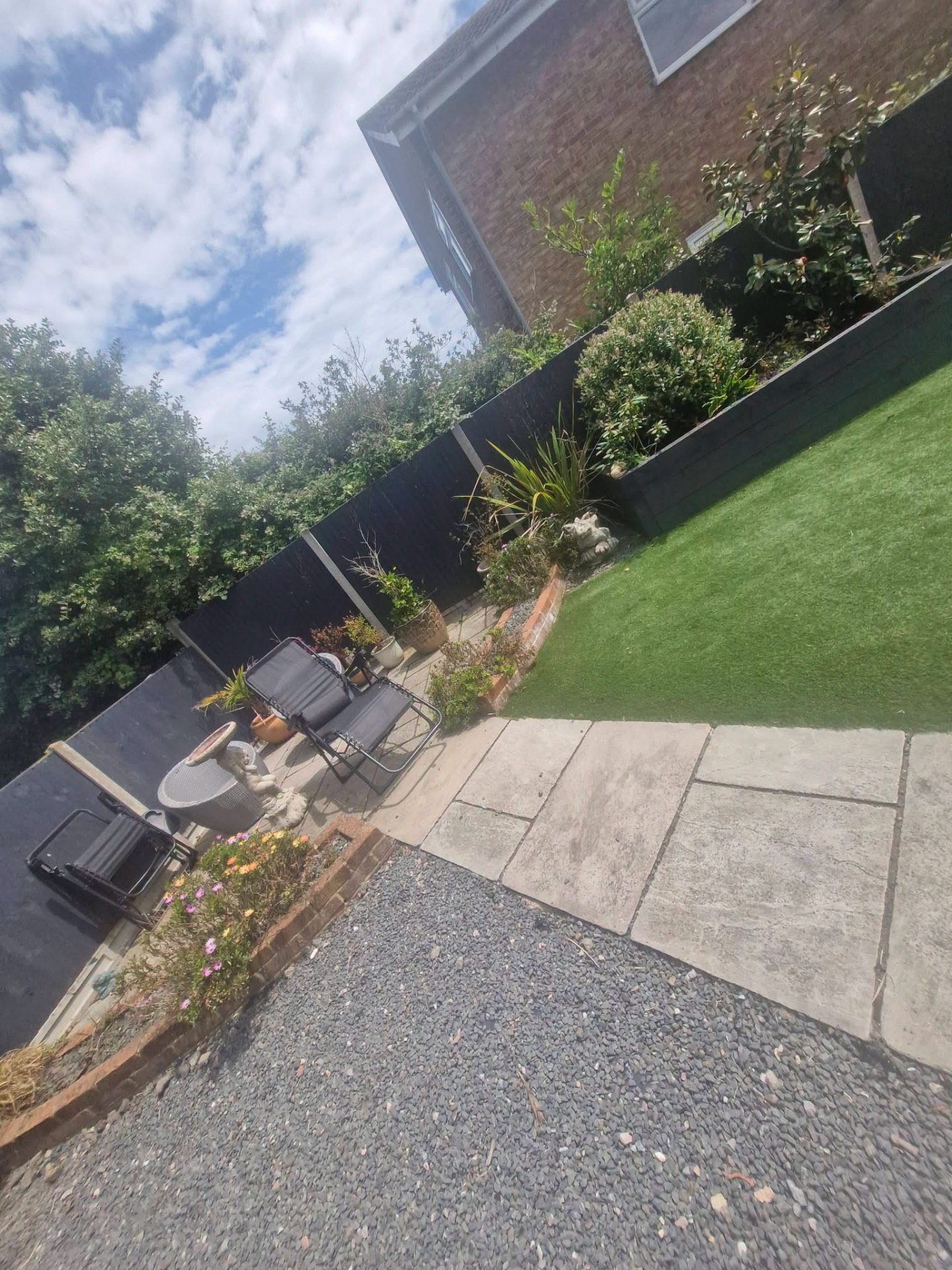Artificial lawn with sandstone patio, raised sleeper beds and seating