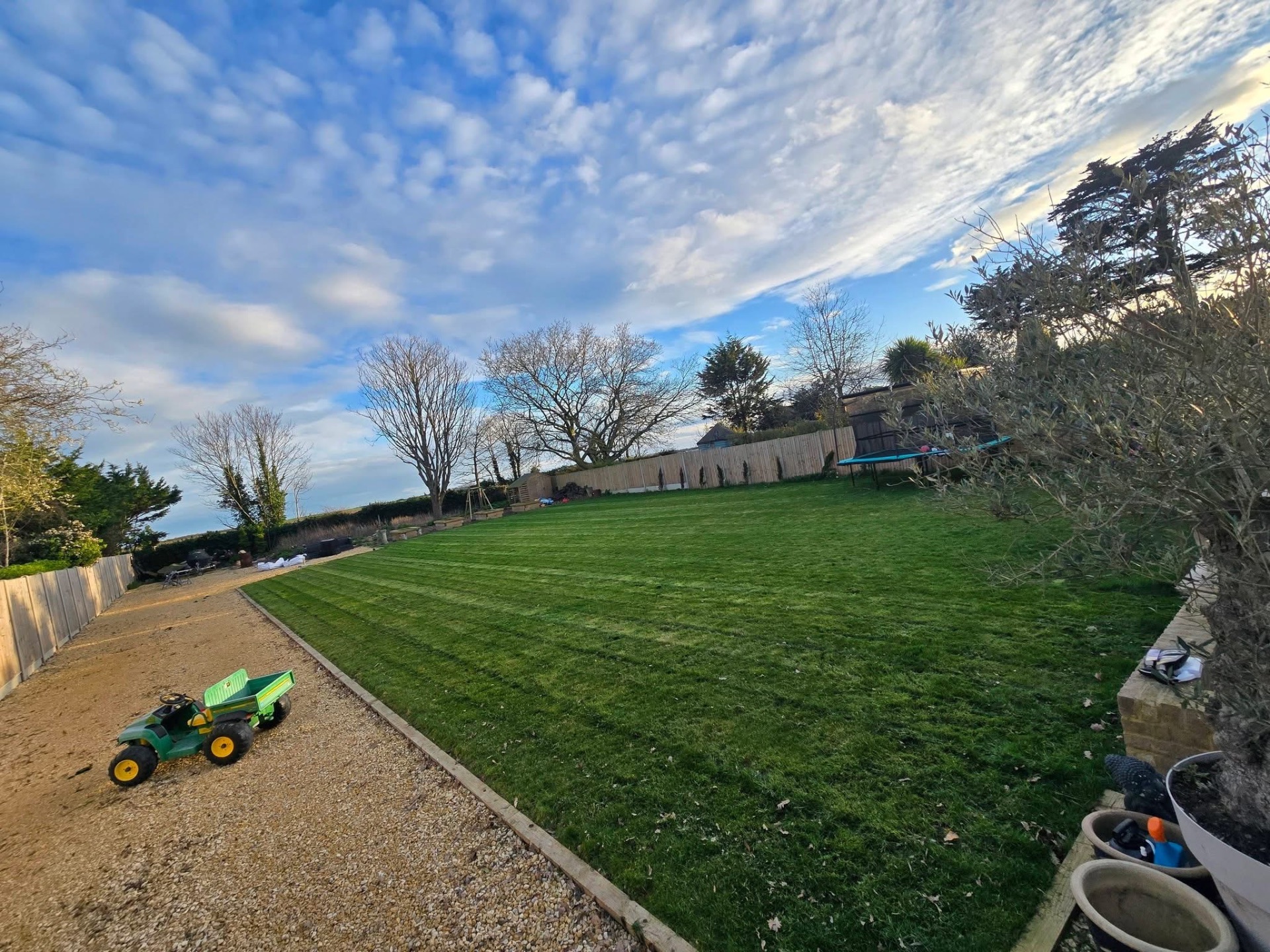 Large striped rear lawn maintained beside gravel path