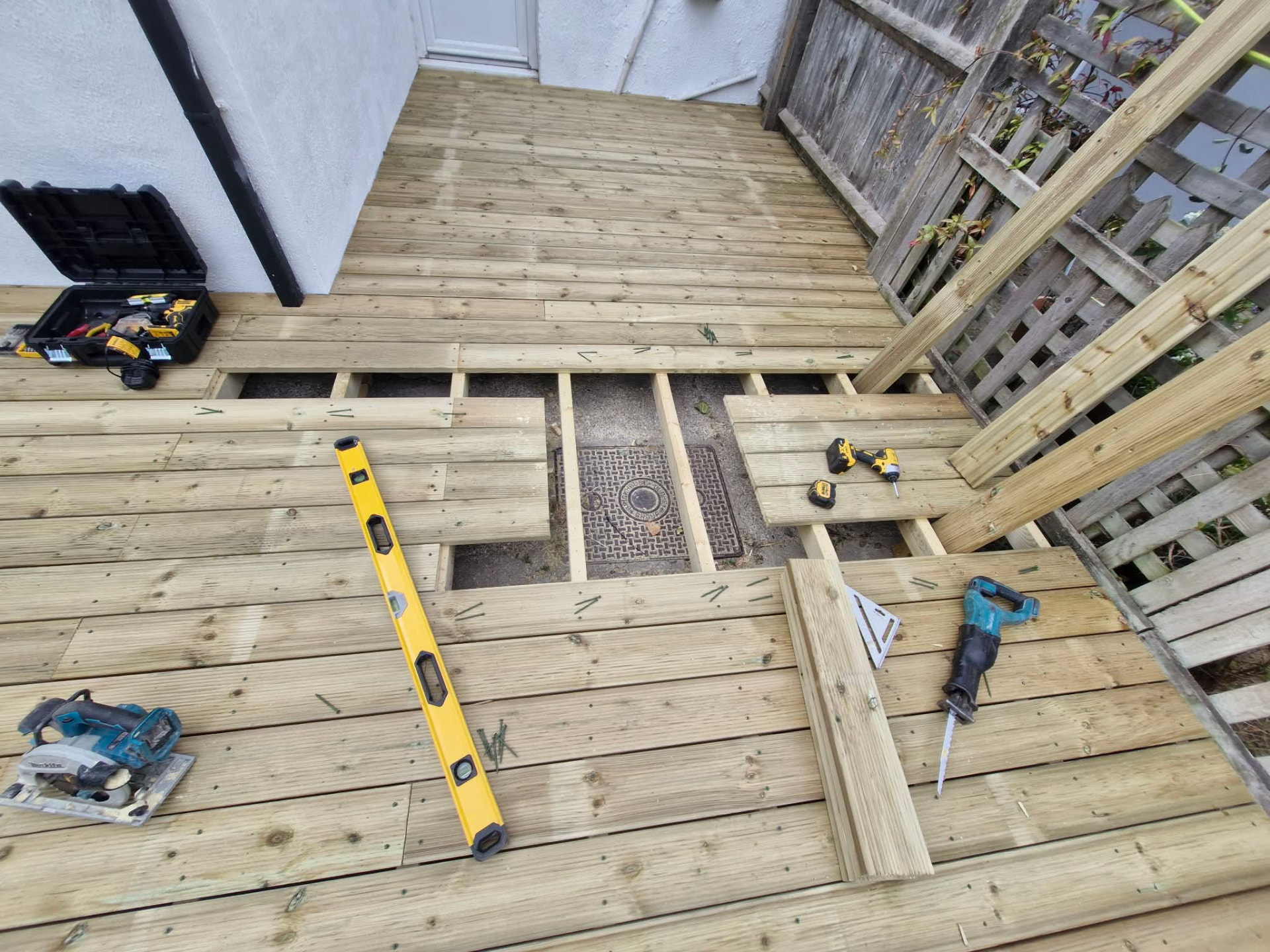 Decking boards being fitted with an inspection hatch left for the manhole