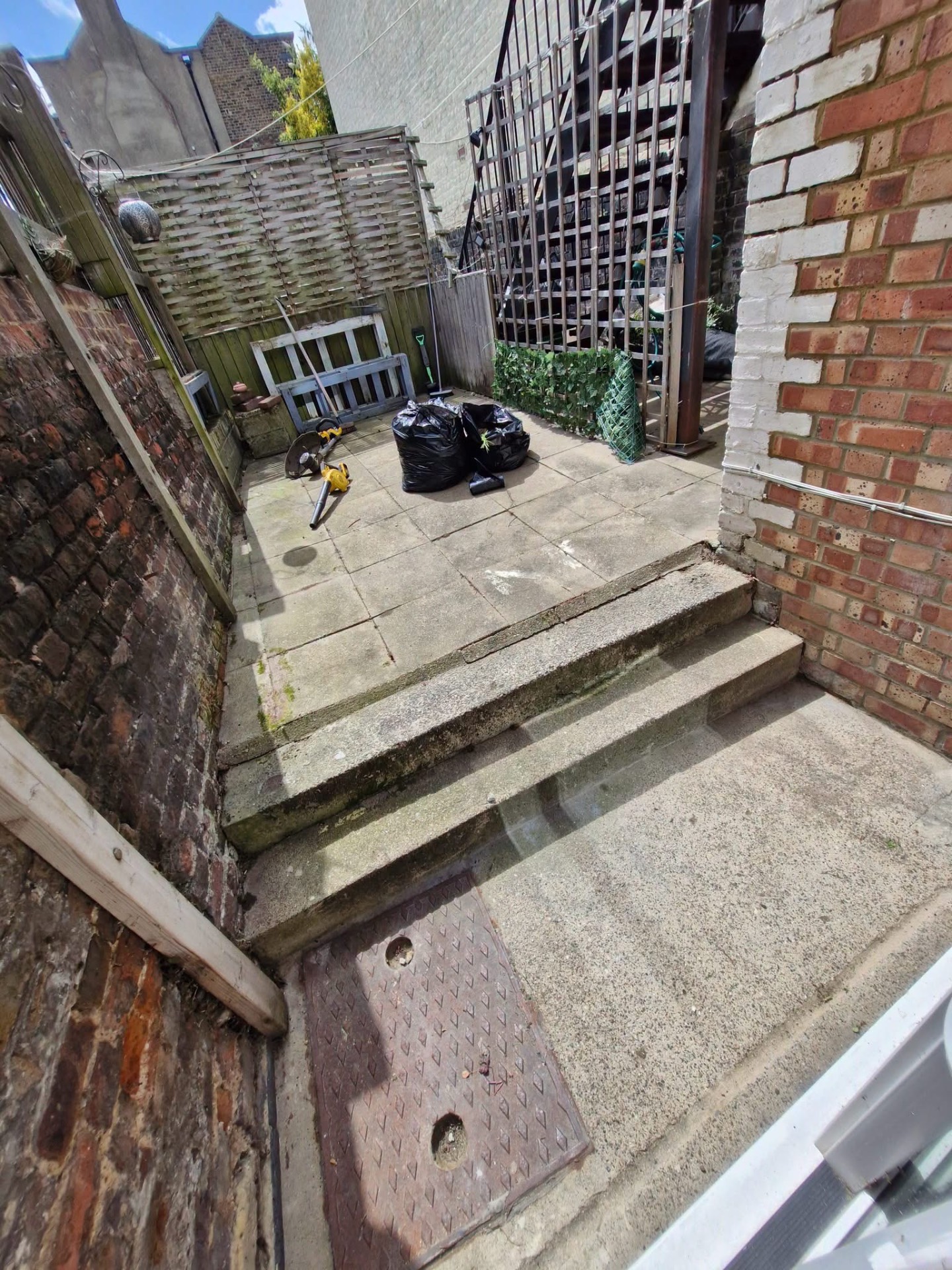 Overgrown rear yard cleared with bagged garden waste ready for removal
