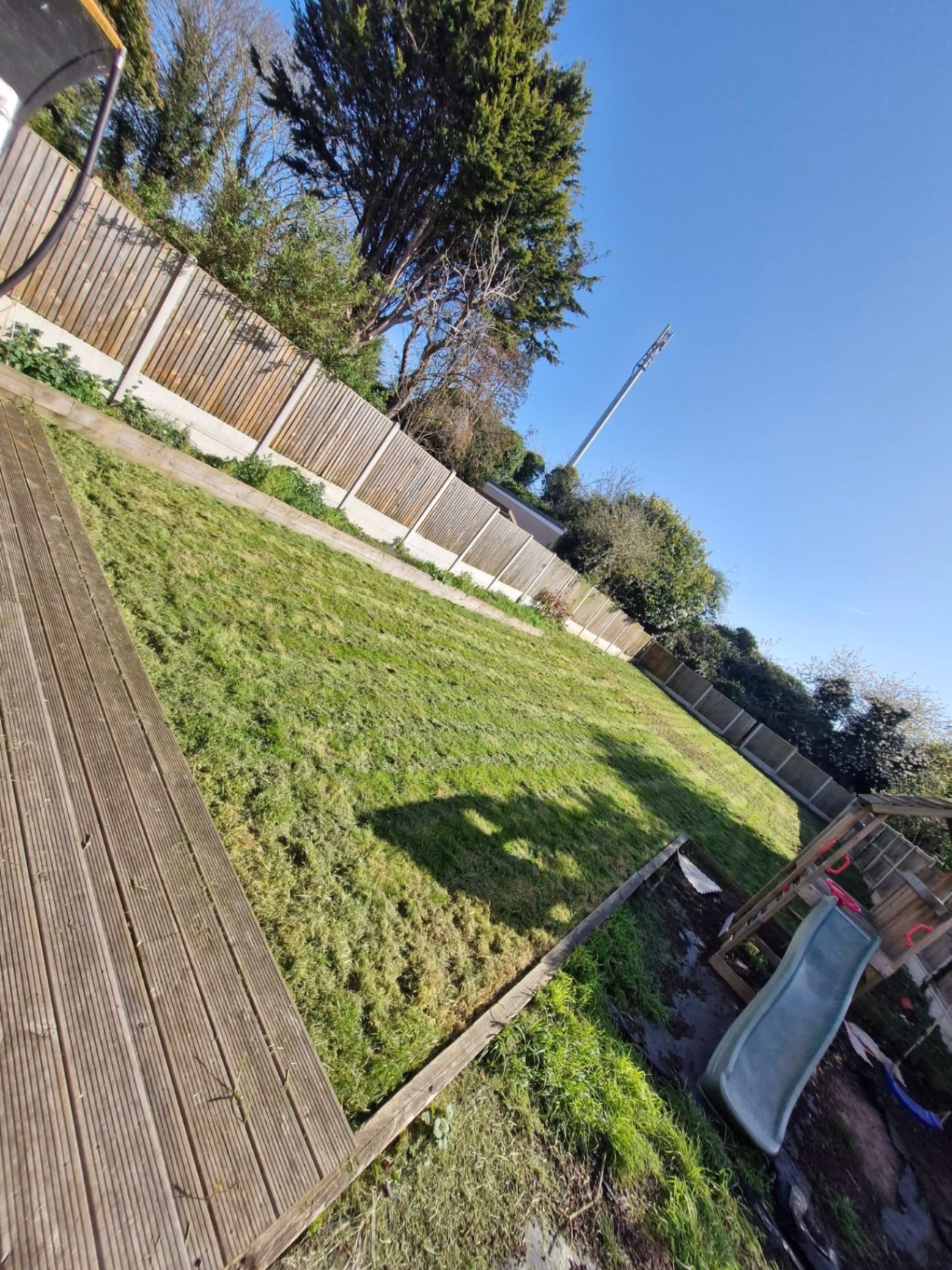Sloped rear lawn cut back alongside timber decking