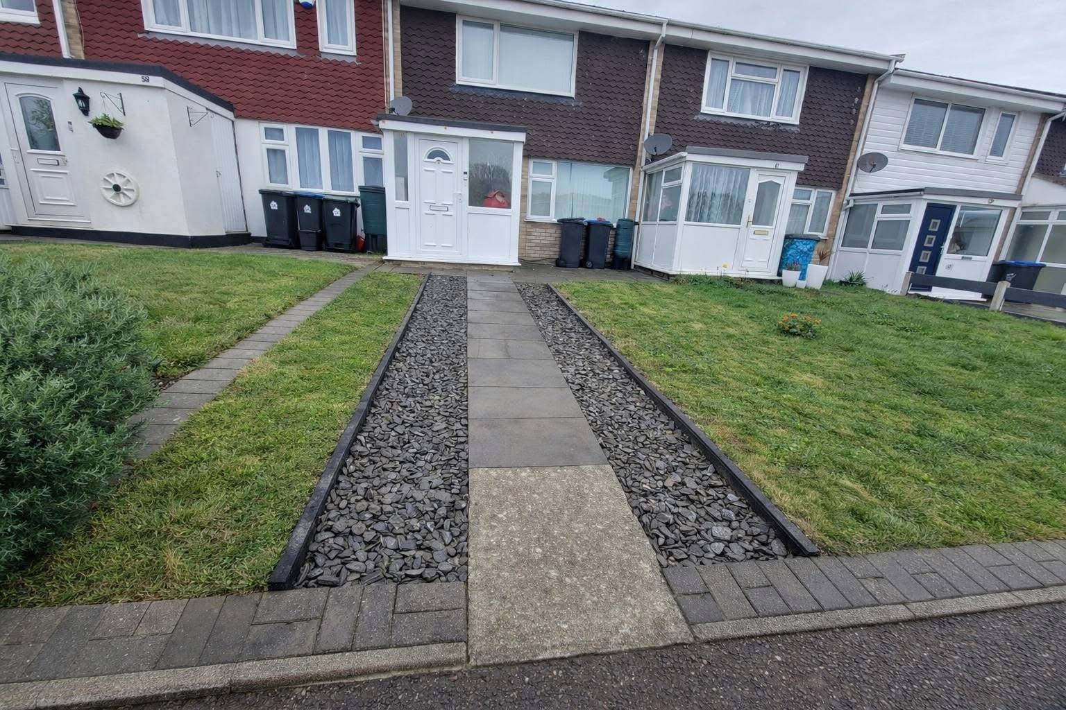 Front garden with slate chippings and paved path between two lawns