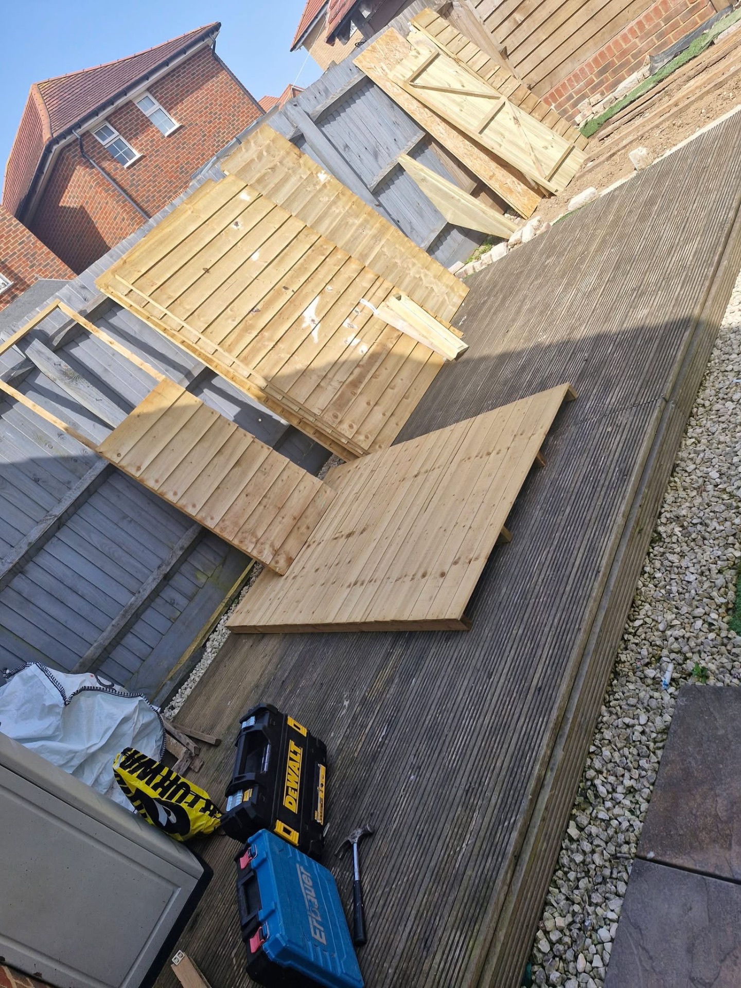 New timber fence panels stacked on decking during boundary install