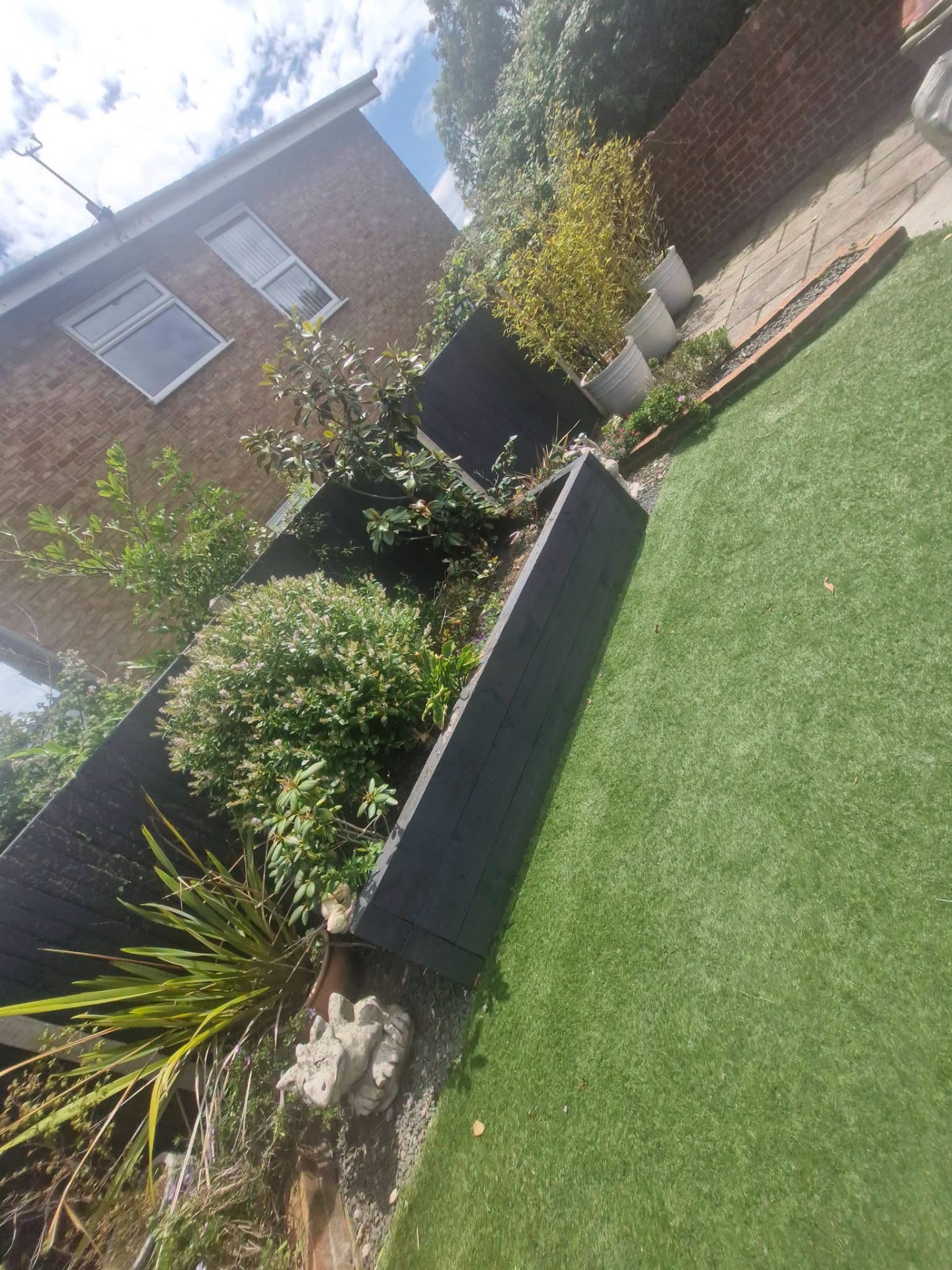Raised sleeper borders trimmed with topiary shrubs and potted bamboo