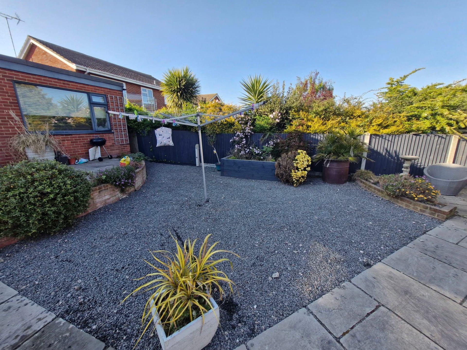 Gravel garden with clothes line, raised planter and mixed shrub borders