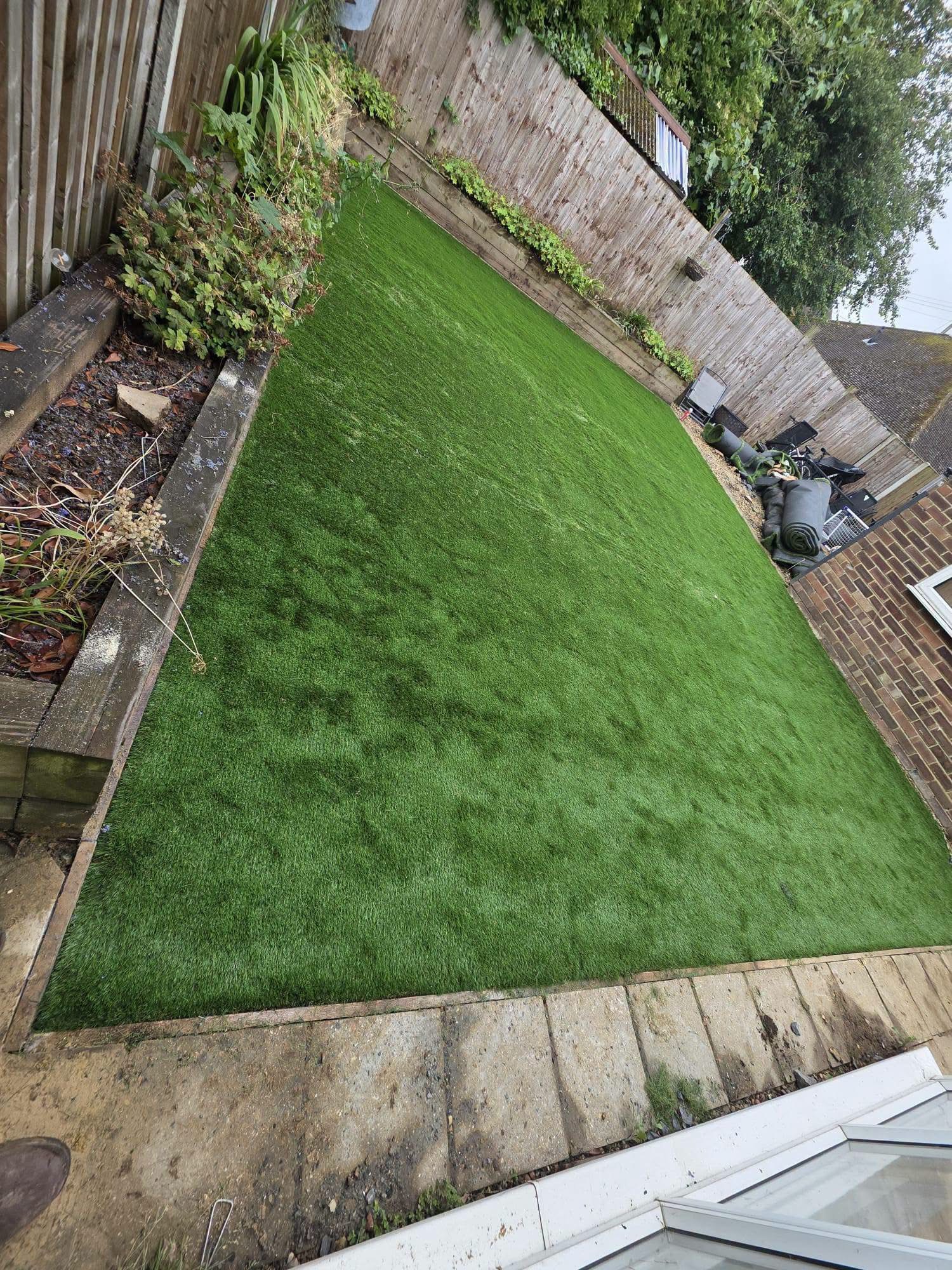 New artificial grass fitted between sleeper borders in rear garden