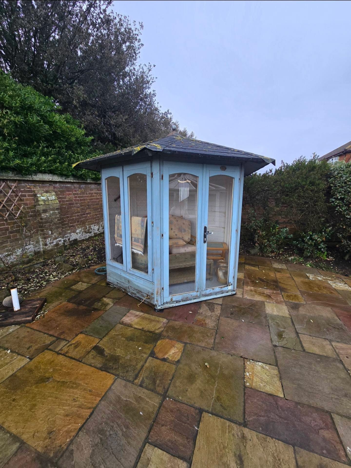 Blue timber summerhouse on Indian sandstone patio