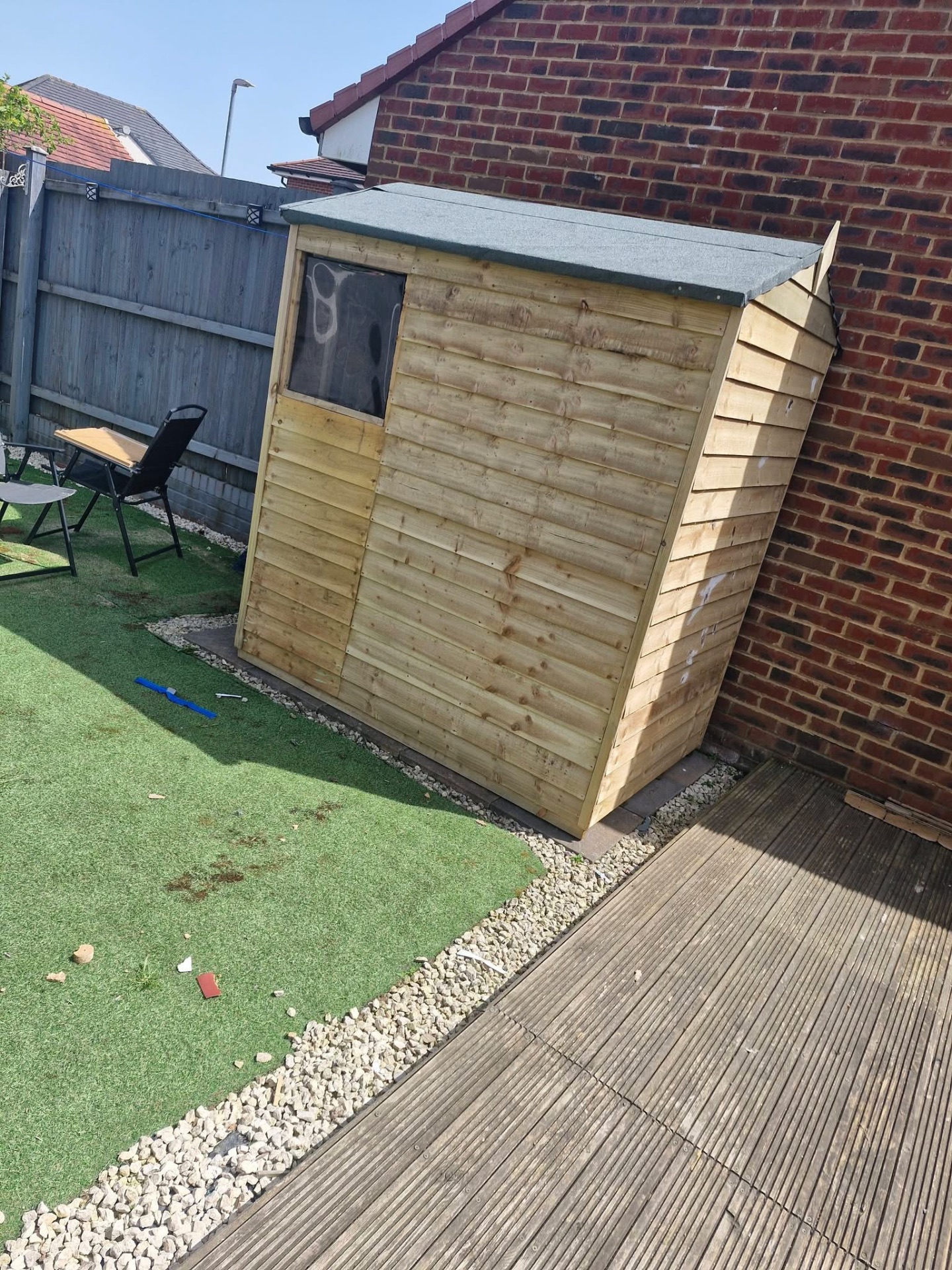 Finished timber garden shed with felt roof beside artificial lawn